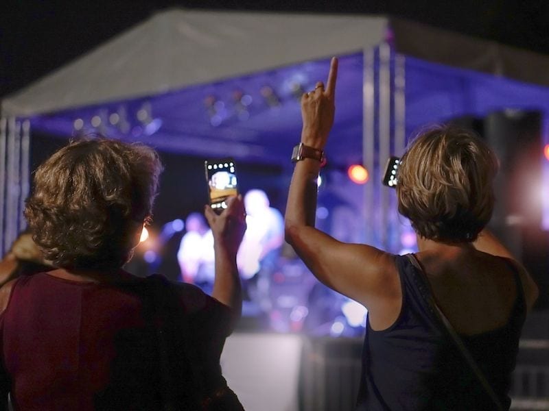 older women taking pictures at a concert